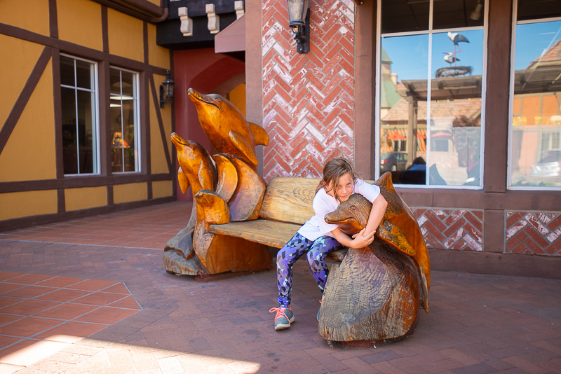 Katie hugging a wooden statue of a dolphin in solvang california