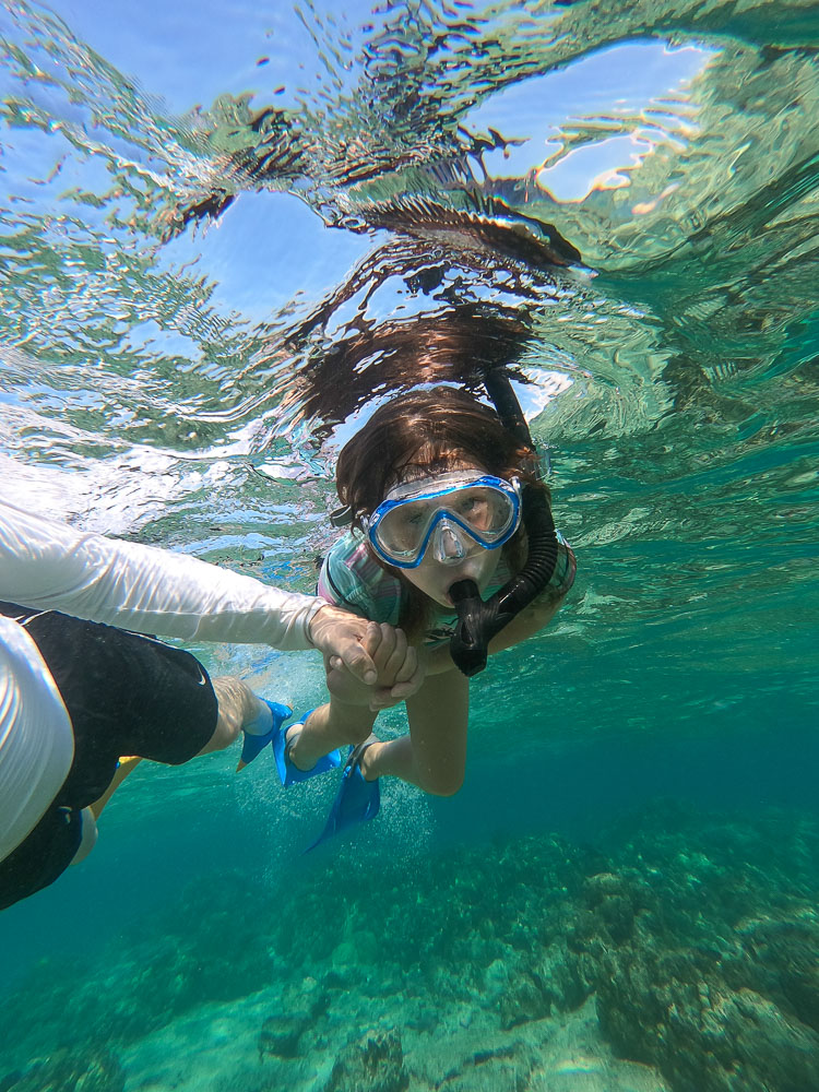 father and daughter snorkeling in hawaii holding hands