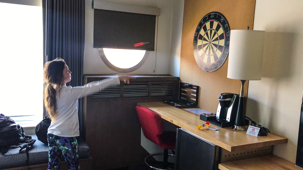 kate playing darts in room in hotel zephyr in san francisco