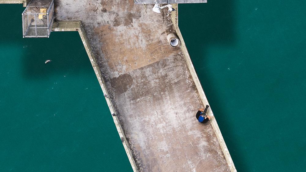 photographer on ocean beach pier viewed from above